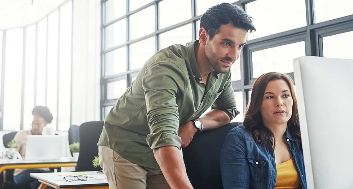 Man showing woman something on the computer in office