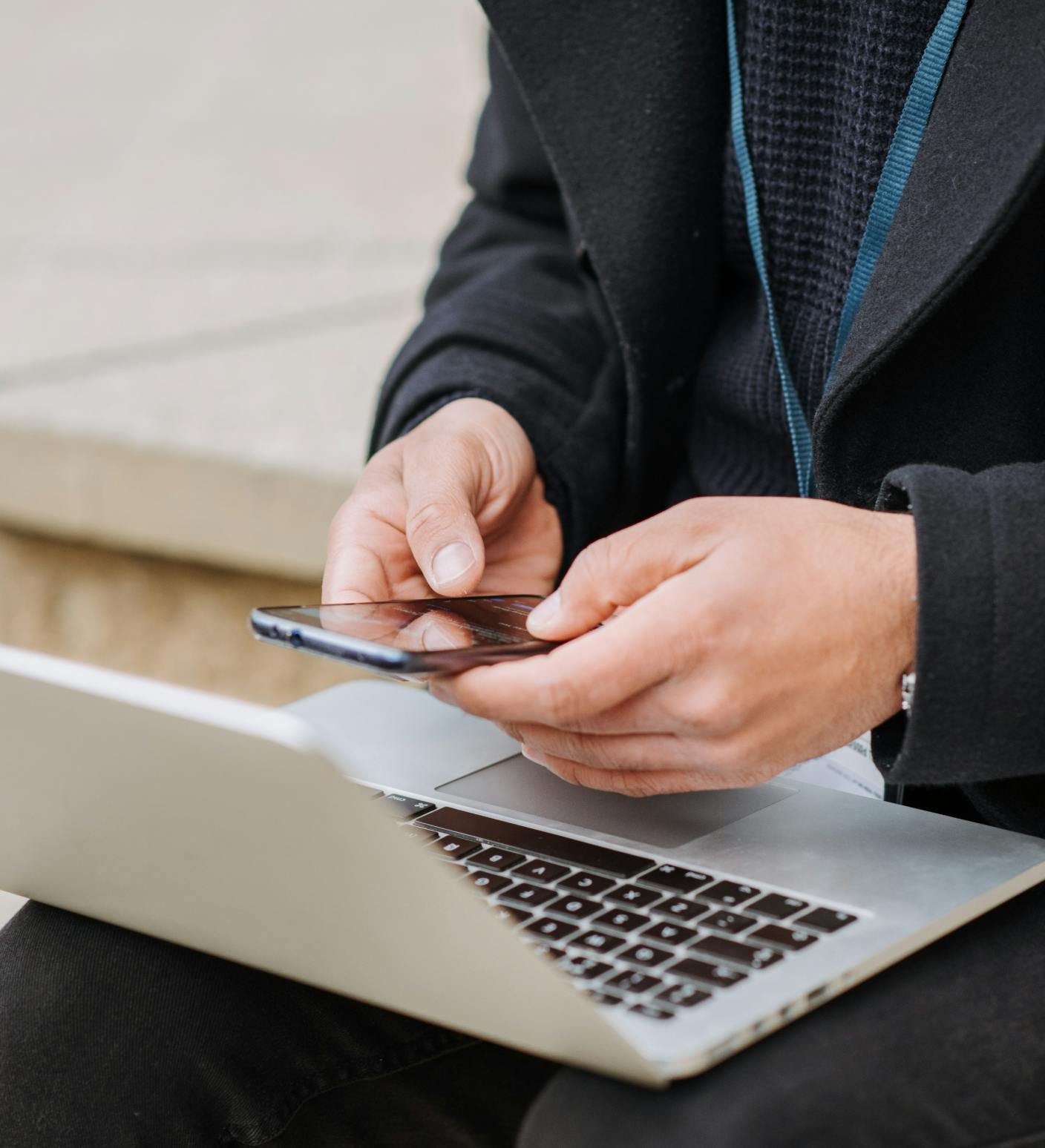 man holding phone and using laptop