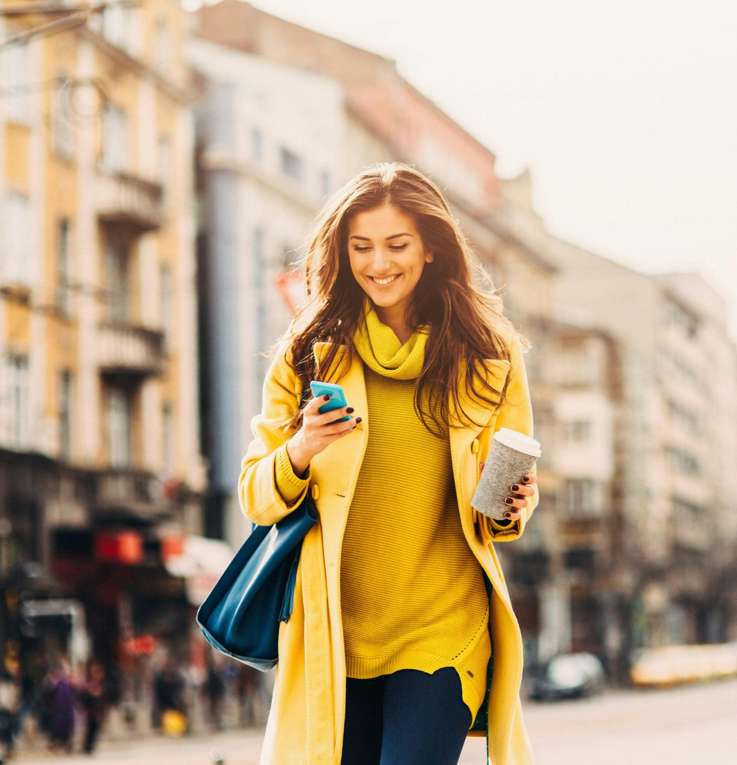 Smiling woman in yellow clothes holding a phone