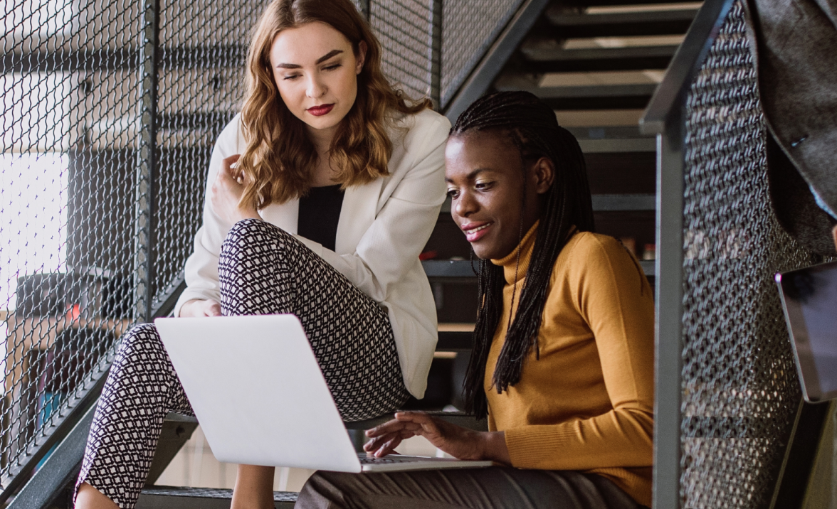coworkers using laptop on stairs