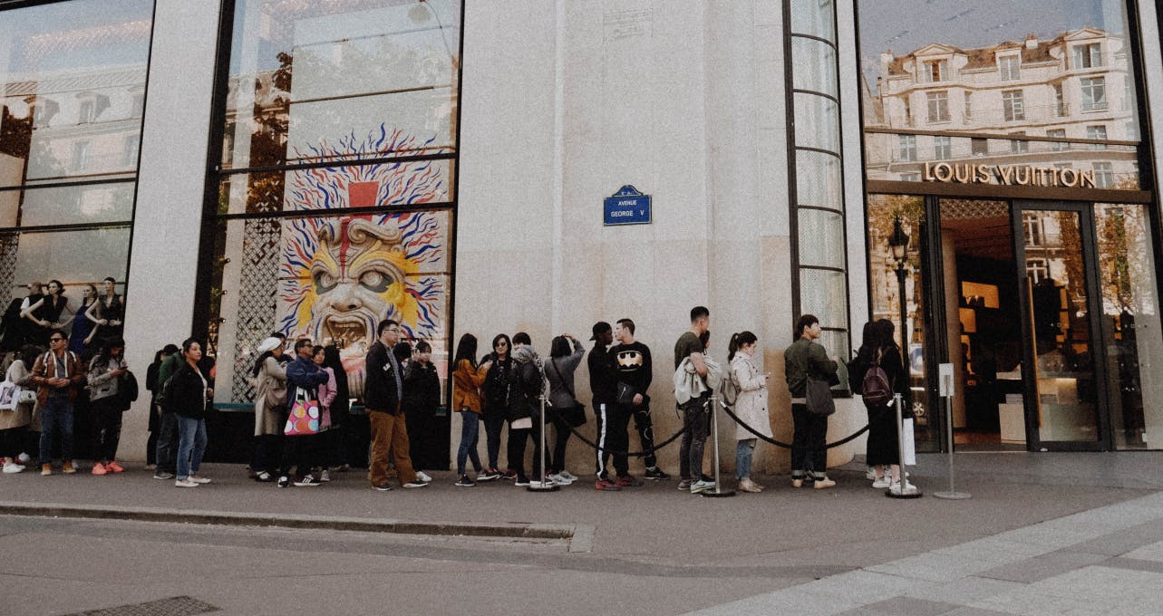 People waiting in a queue outside of a business.