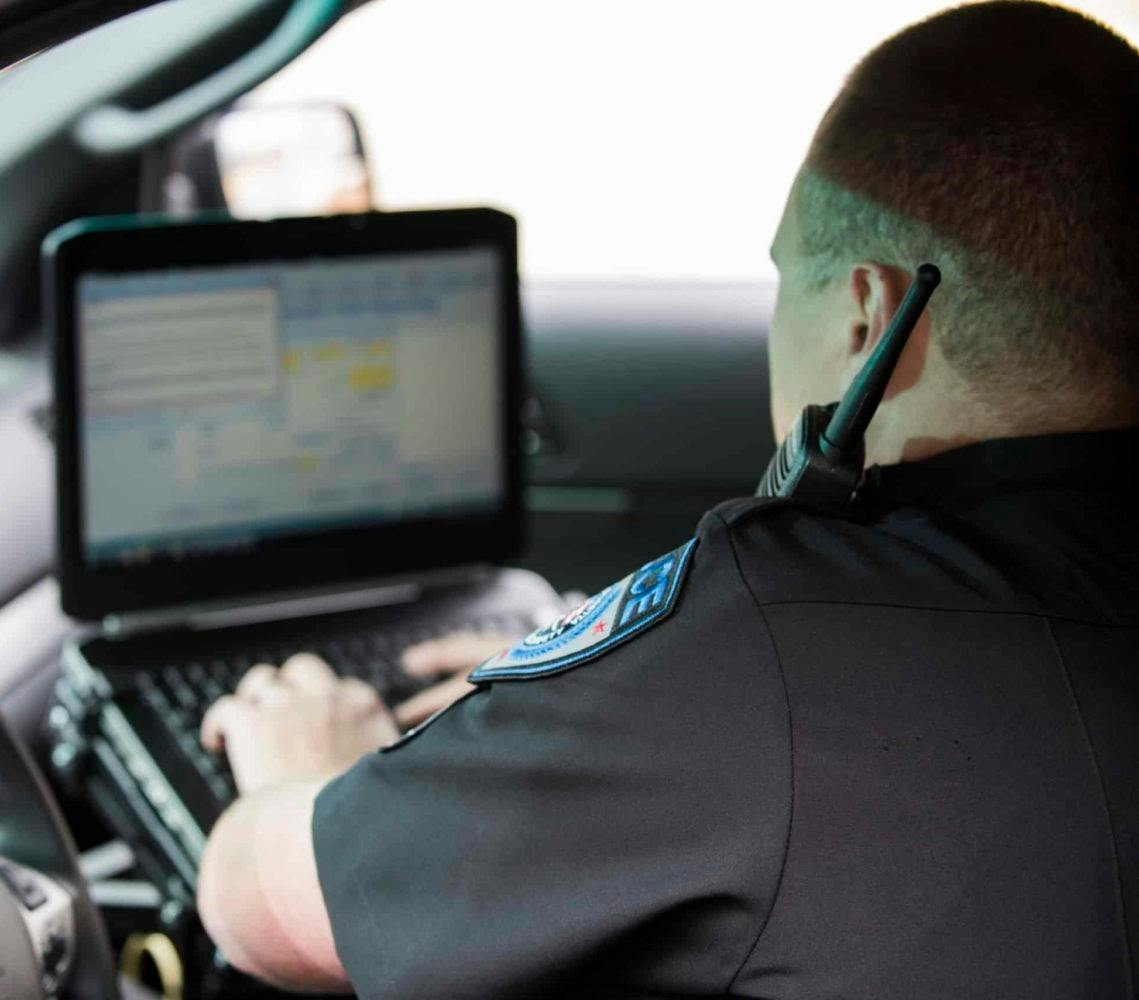 Cop in car looking at computer on dashboard