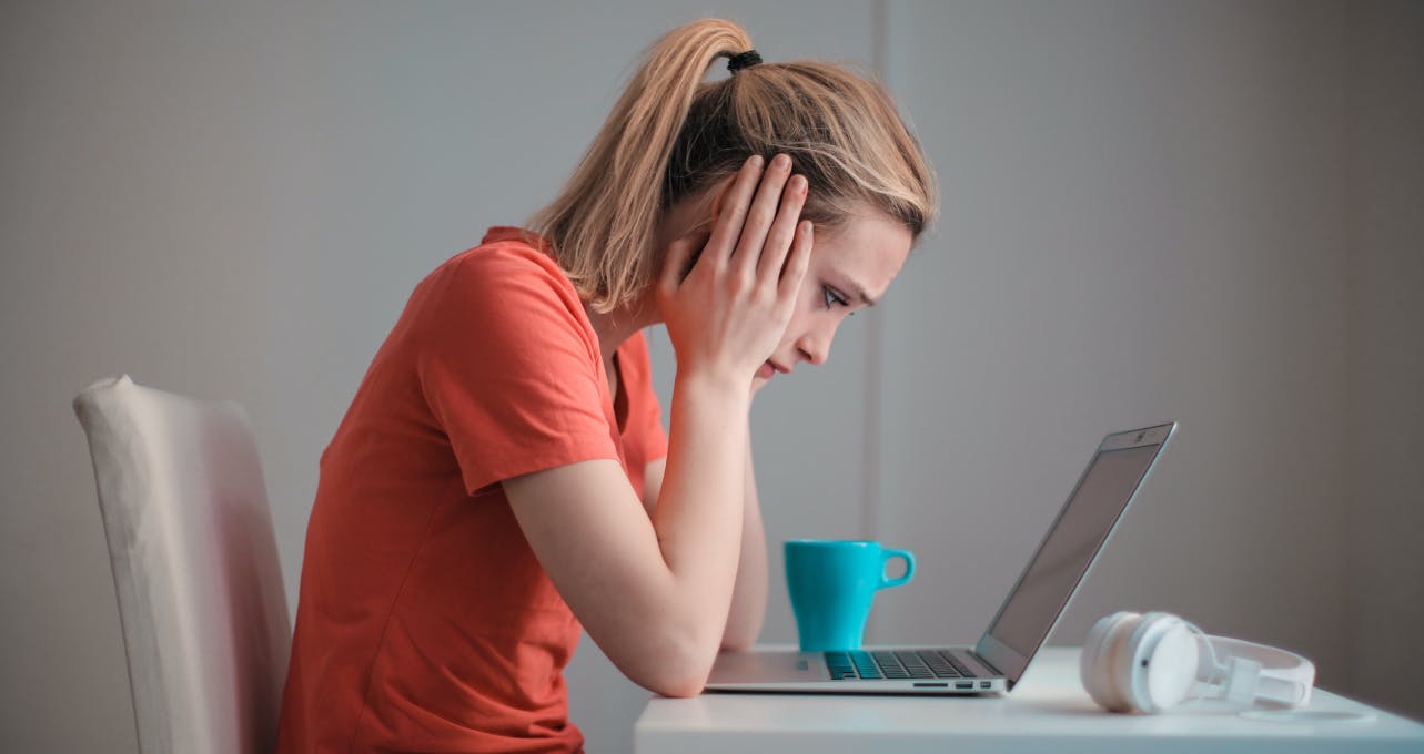 Customer at personal computer with head in hands.