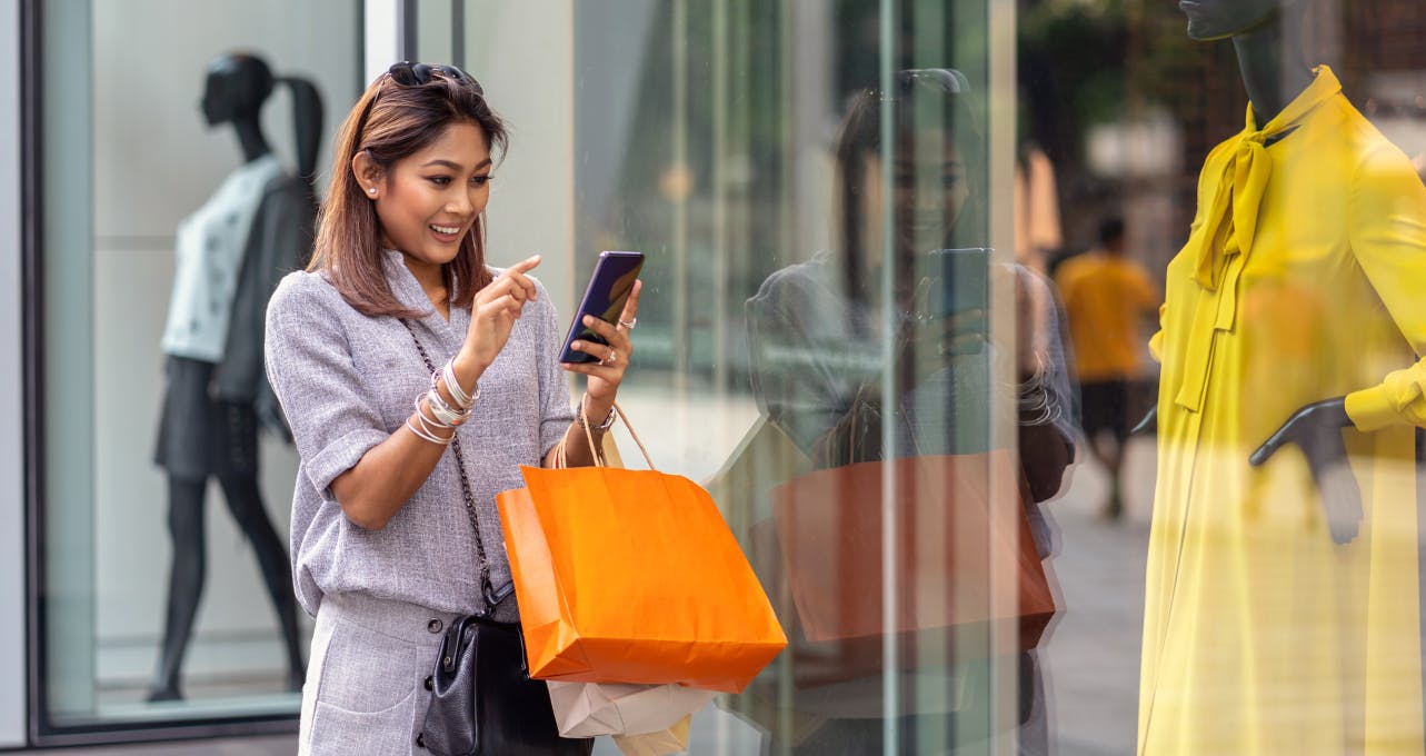 Luxury retail shopper with an orange bag and a phone