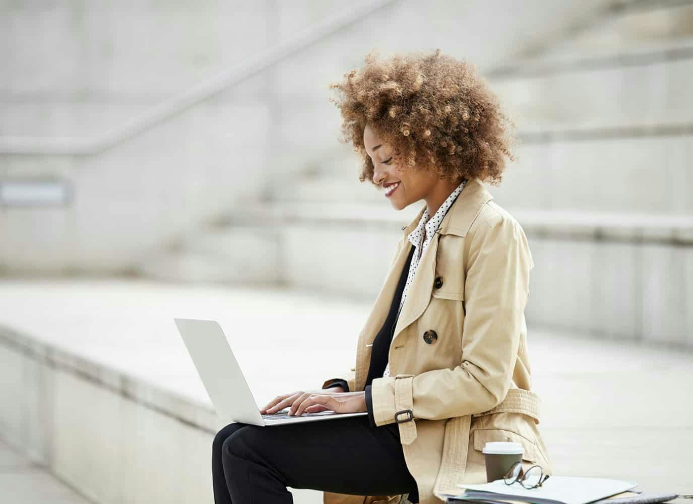 Woman sitting on outdoor steps working on her laptop