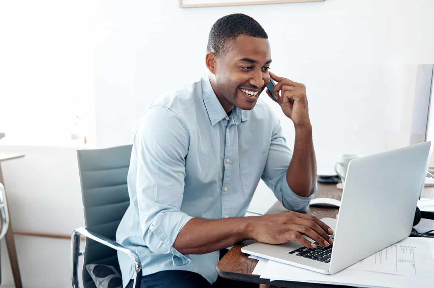 Man sitting at desk smiling at computer