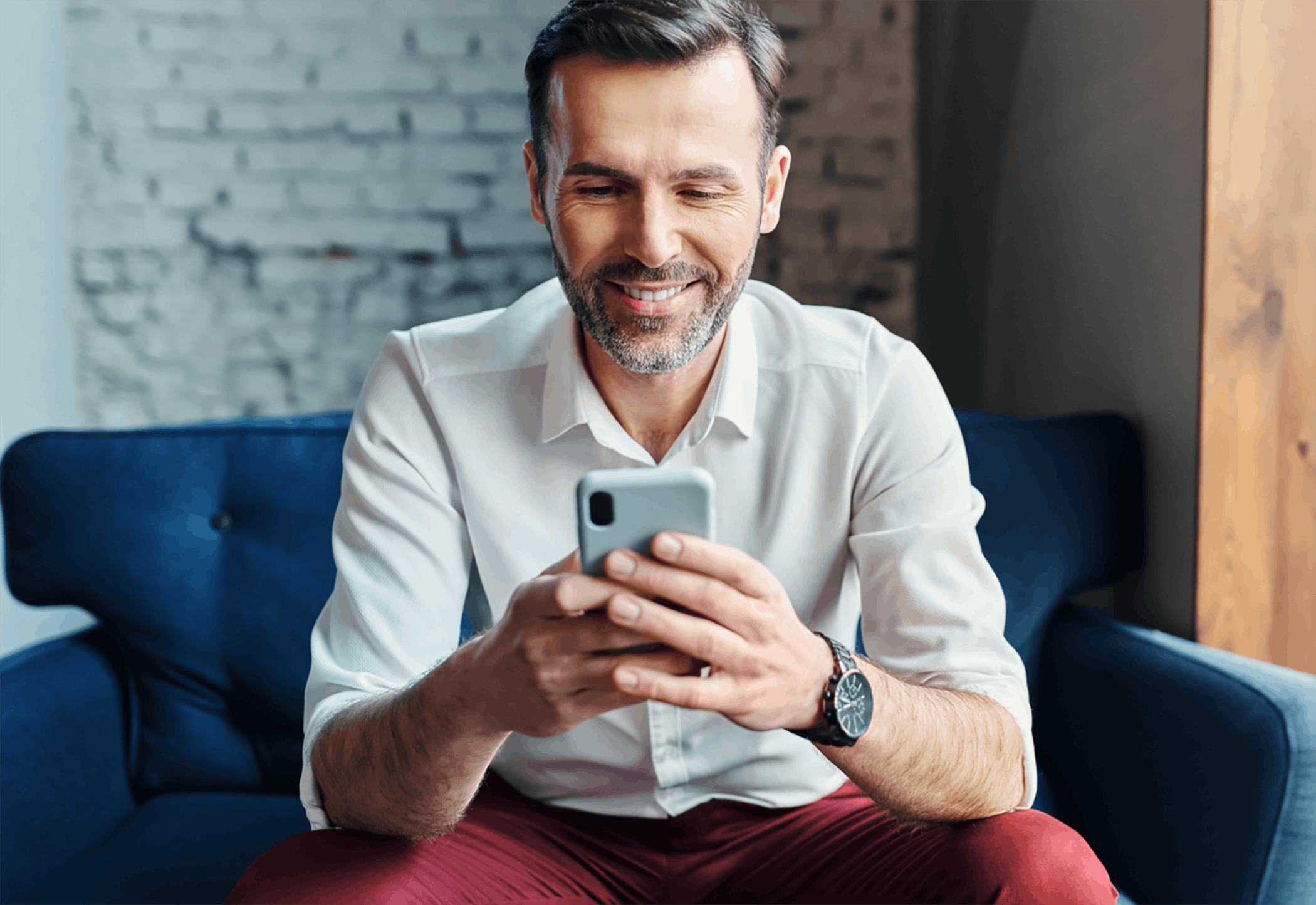 Man texting on phone sitting on chair inside