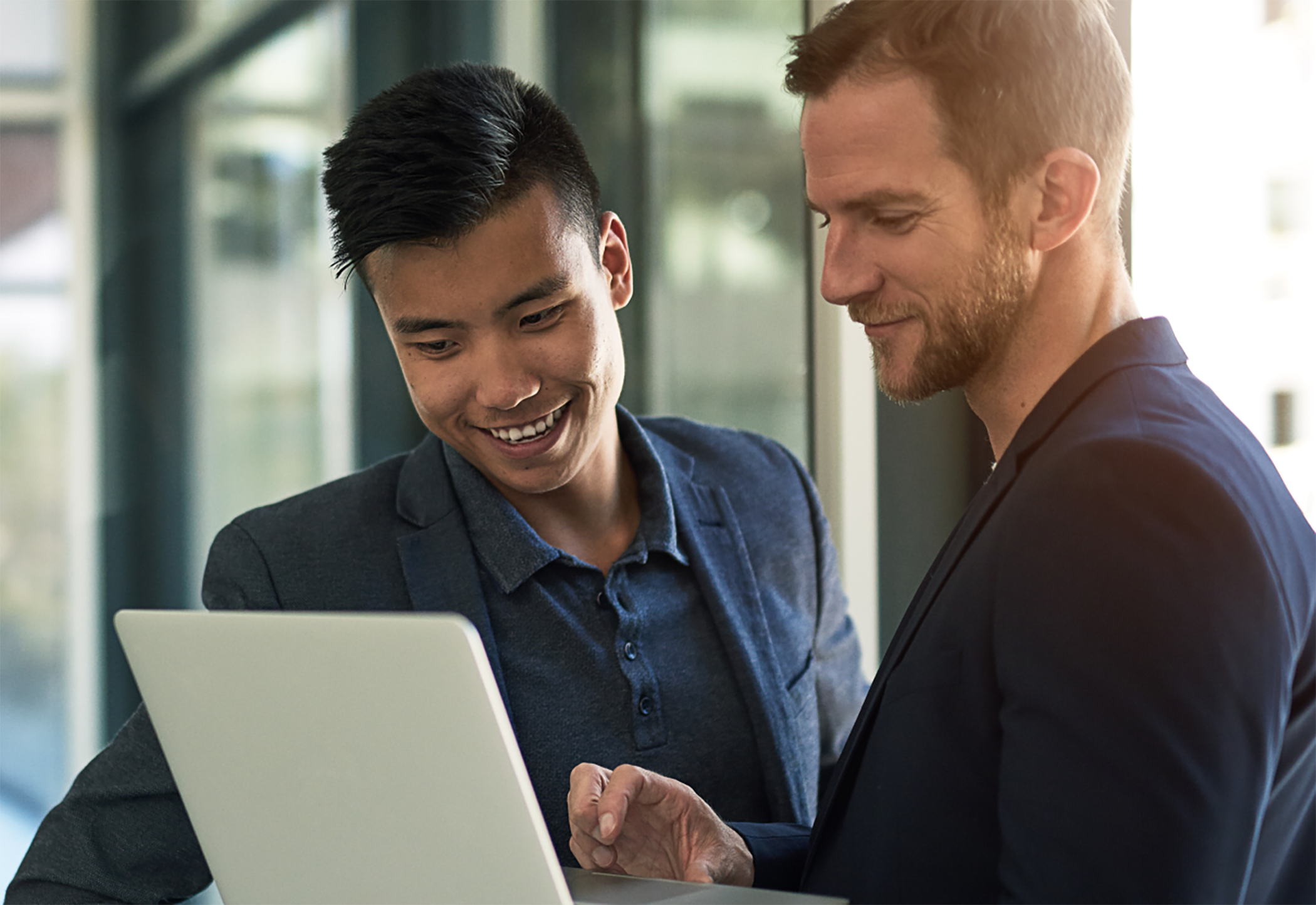 Two men standing meeting on laptop