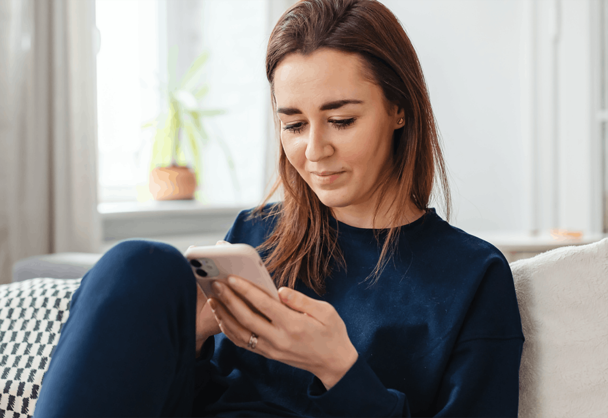 Woman texting from home sitting on couch