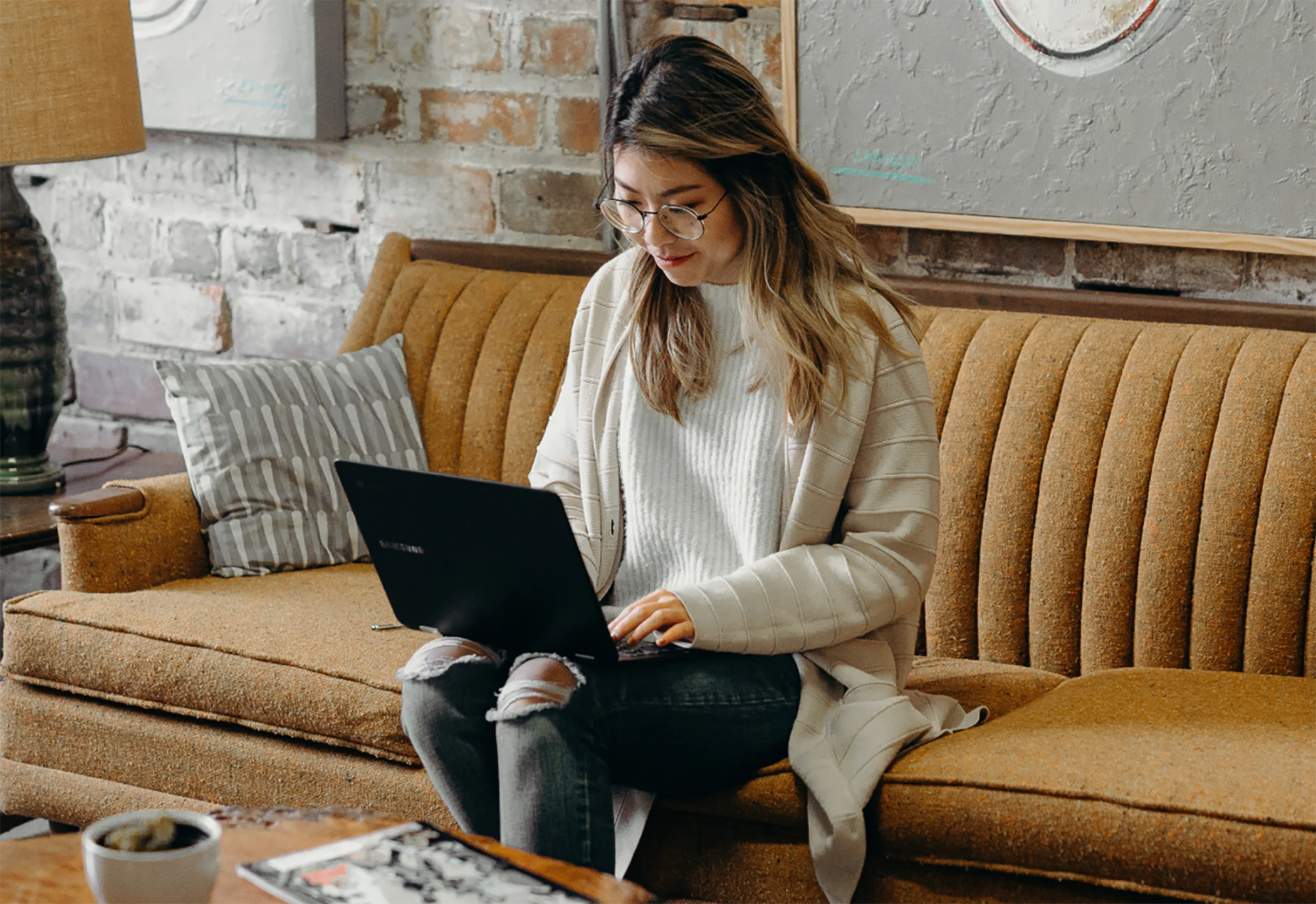 Woman working remote on laptop sitting on couch