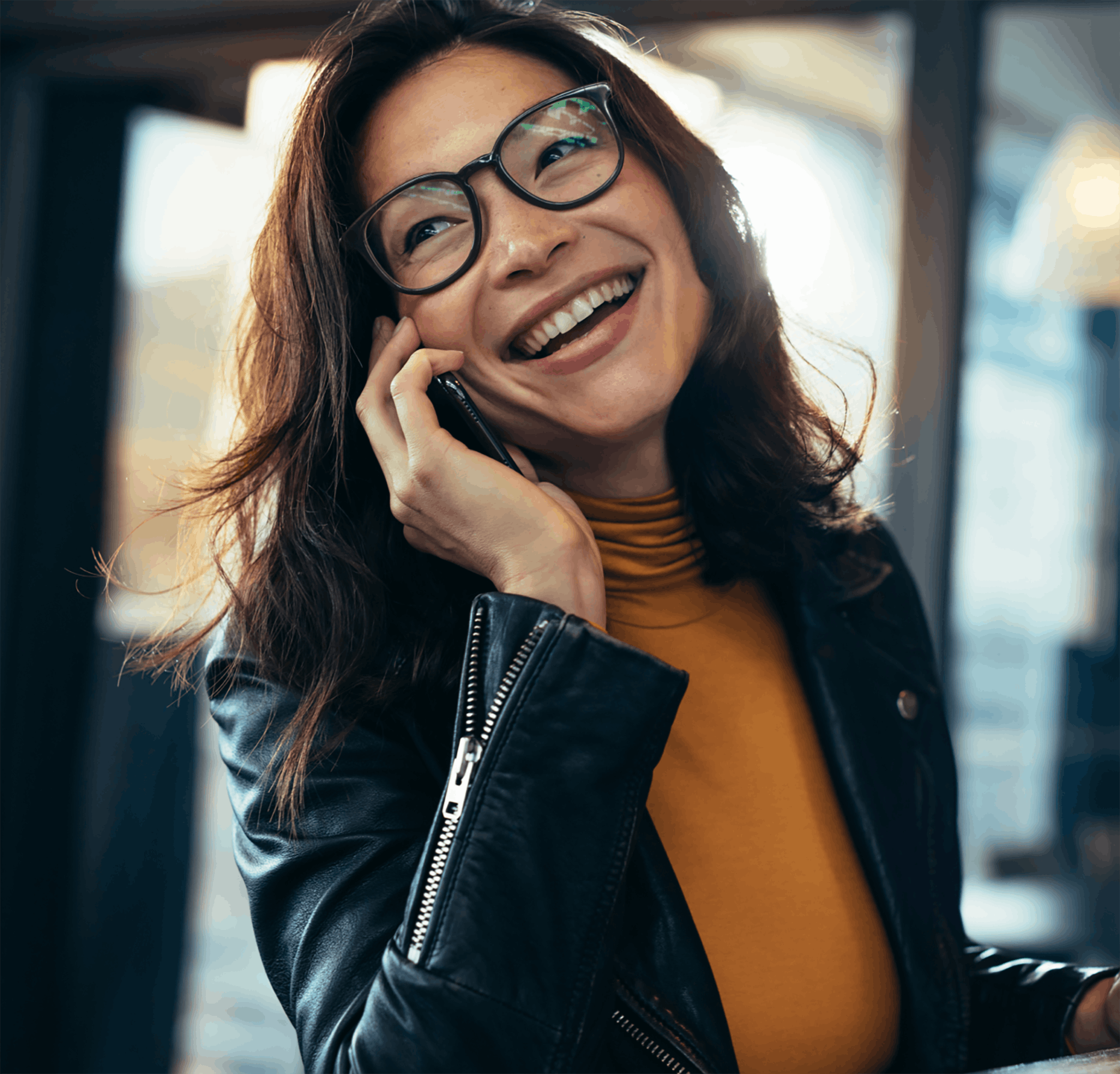 woman with glasses smiling and talking on the phone