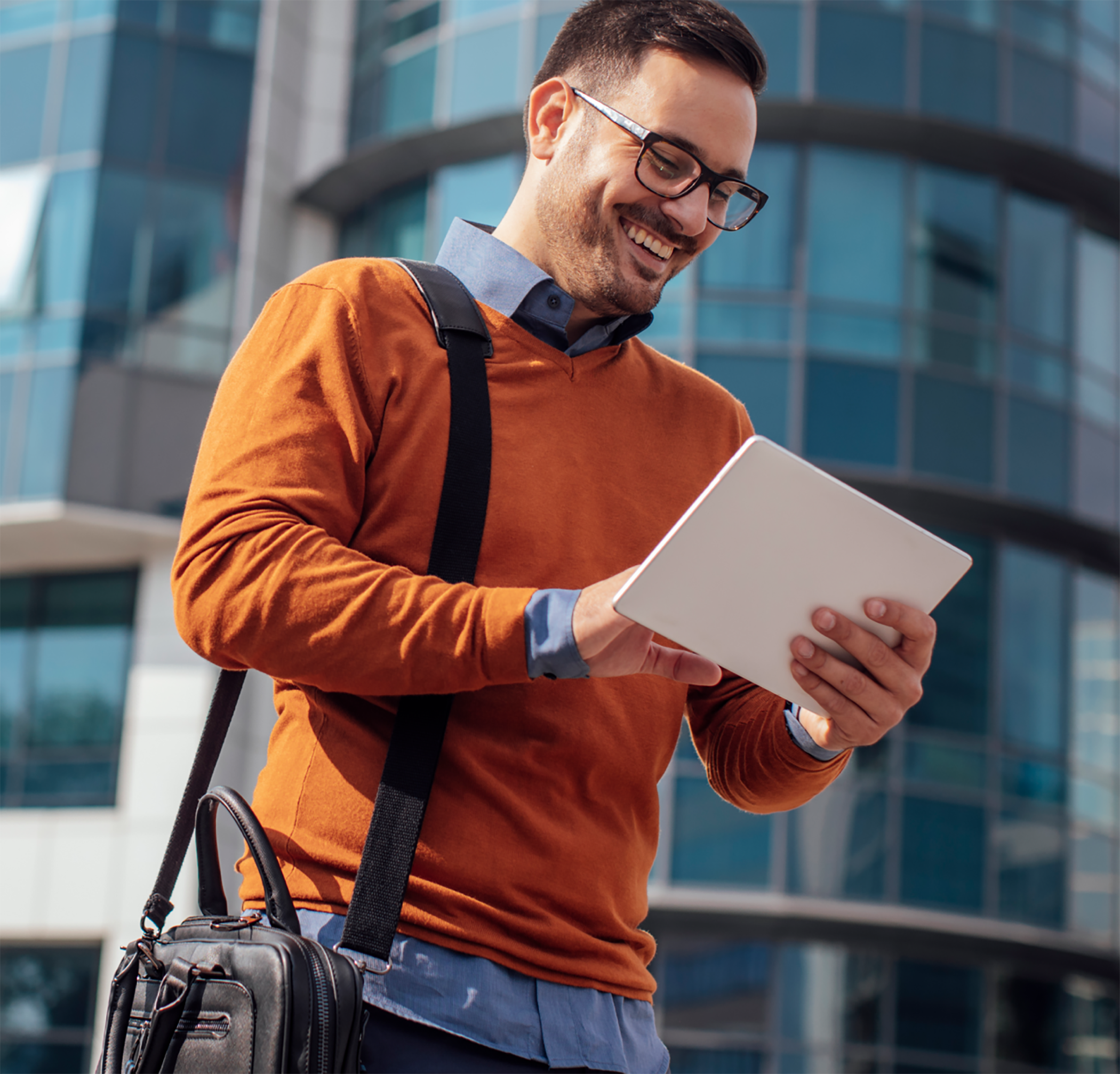 man in orange sweater holding tablet outside