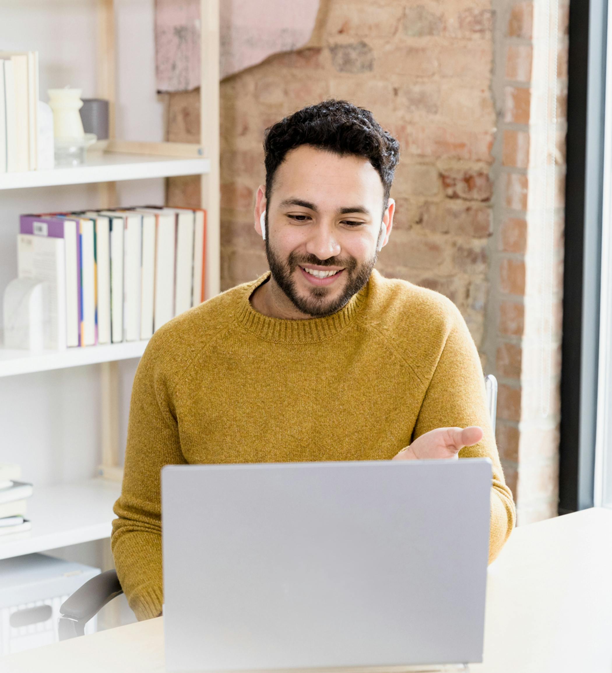 Man in a yellow sweater sits in front of a laptop