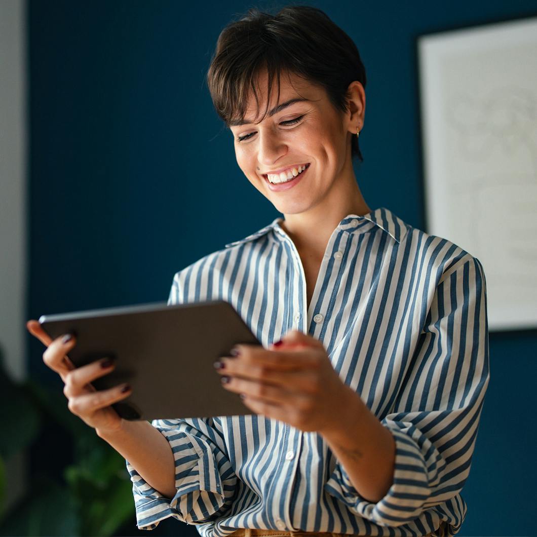 Smiling women in stripped shirt holding a tablet