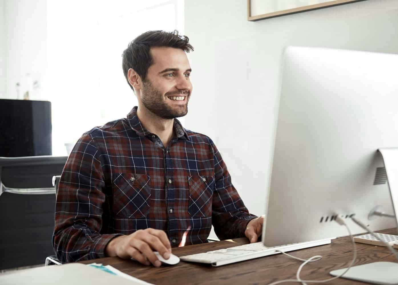 Man working at a desk on computer smiling