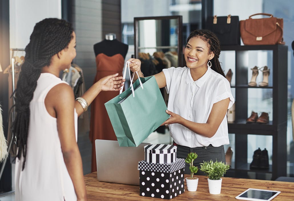woman handing a customer shopping bag to a customer