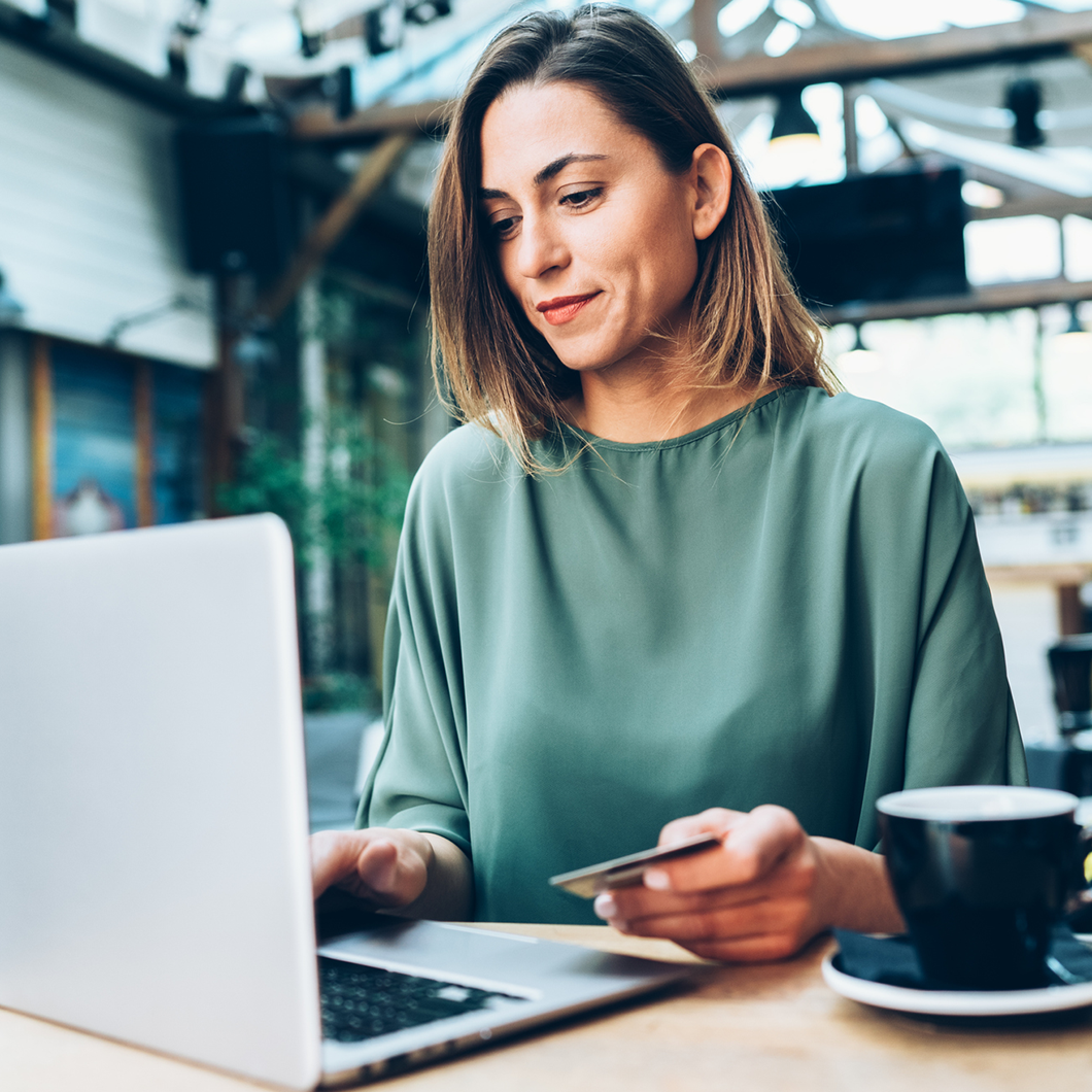 Woman sitting at a laptop with a credit card in hand