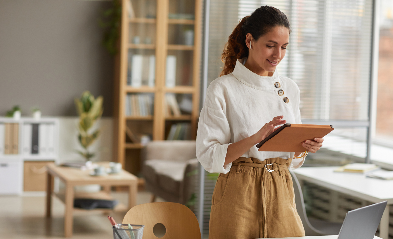 Woman in a white shirt is holding a tablet